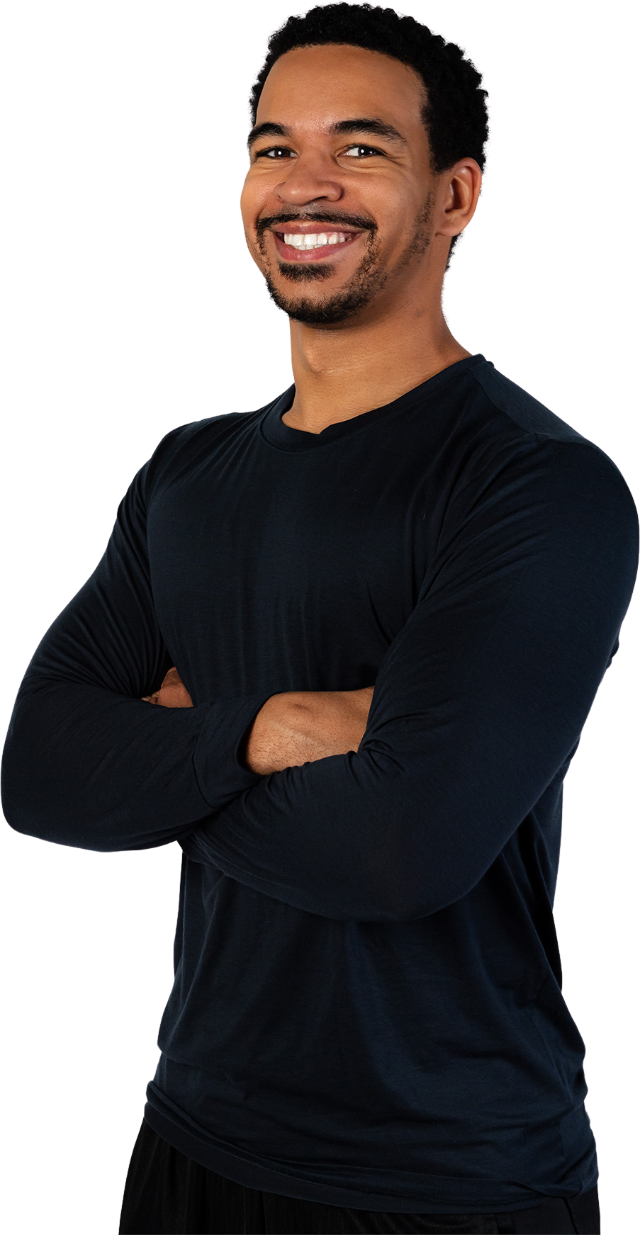 A man in a black shirt is standing with his arms crossed and smiling.