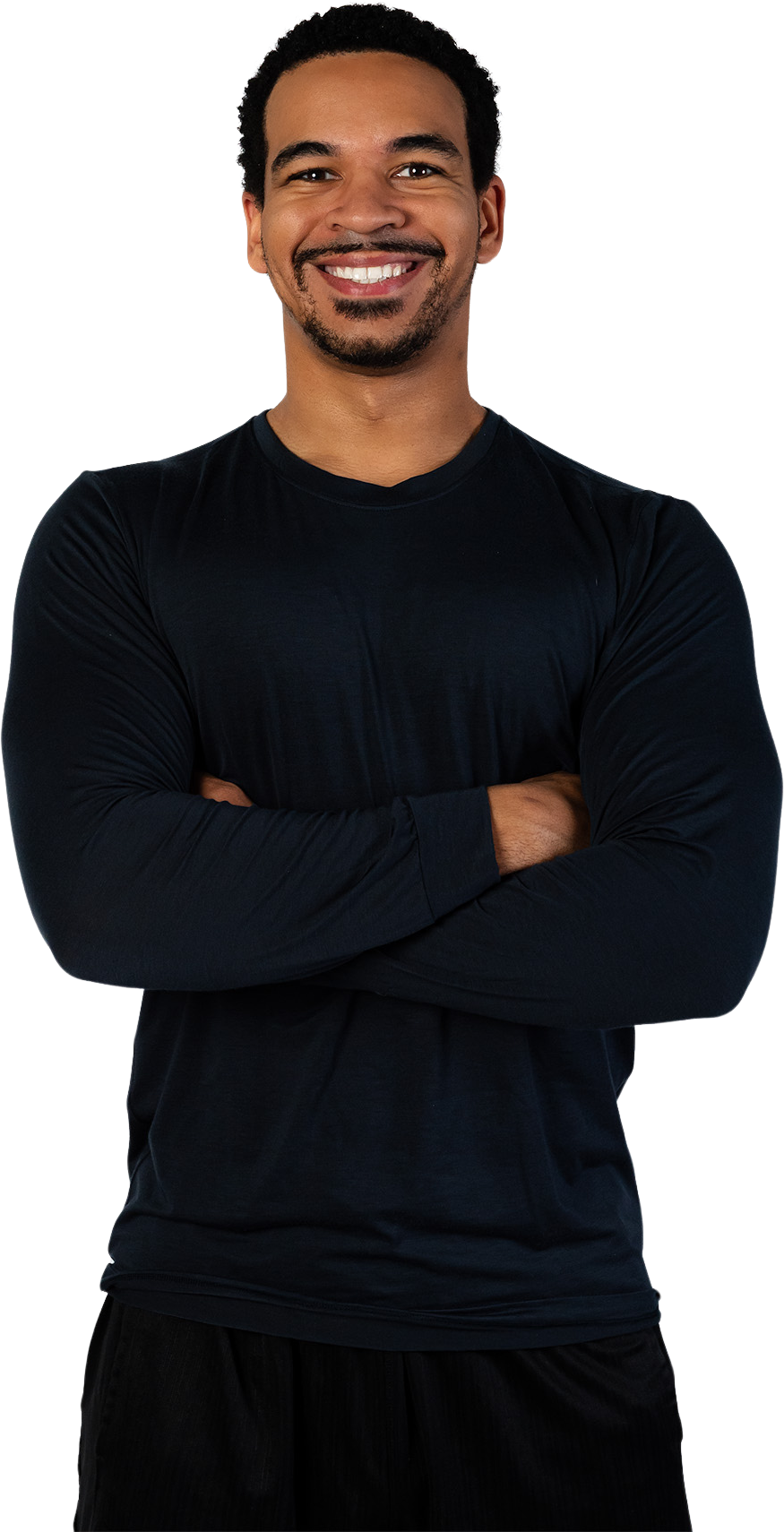 A man in a black shirt is standing with his arms crossed and smiling.