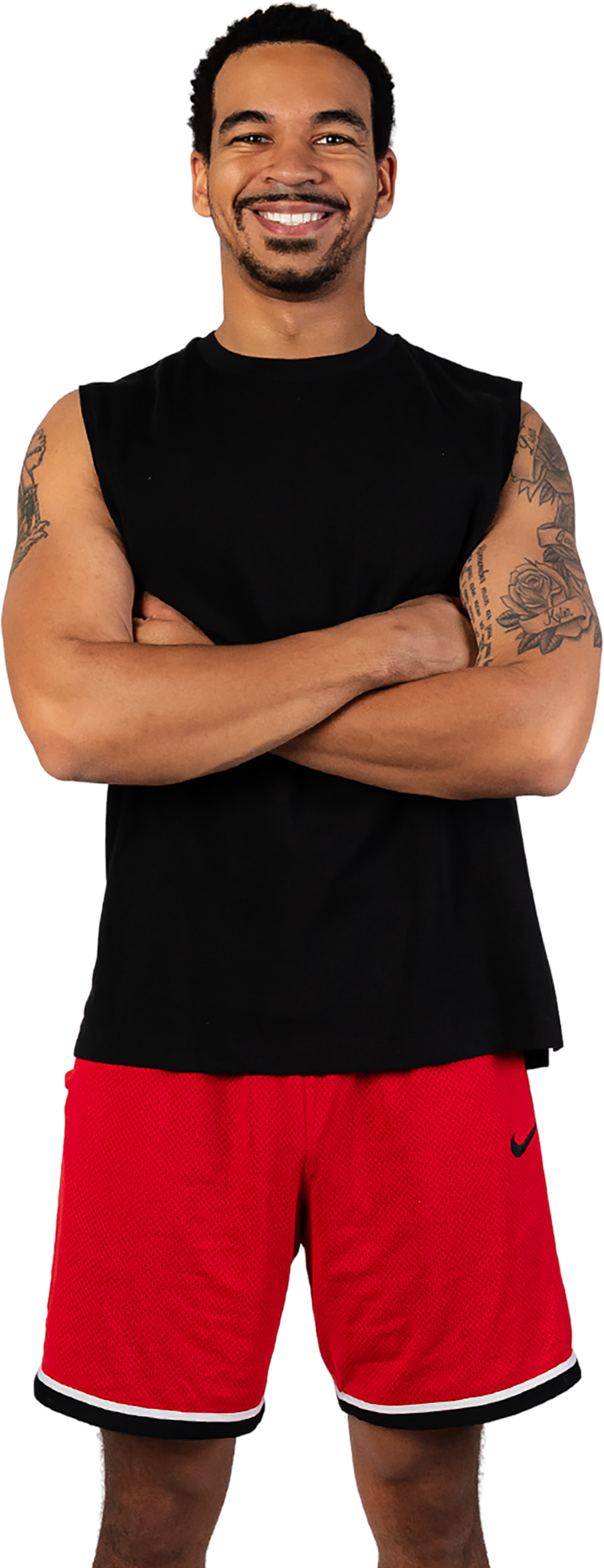 A man in a black tank top and red shorts is standing with his arms crossed.