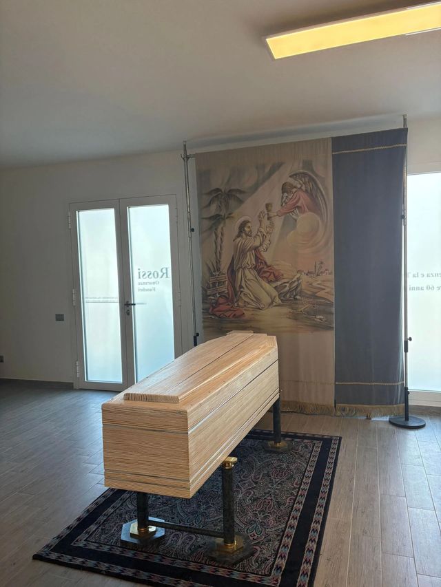 Woven casket on a patterned rug in a bright room with doors and a large wall mural
