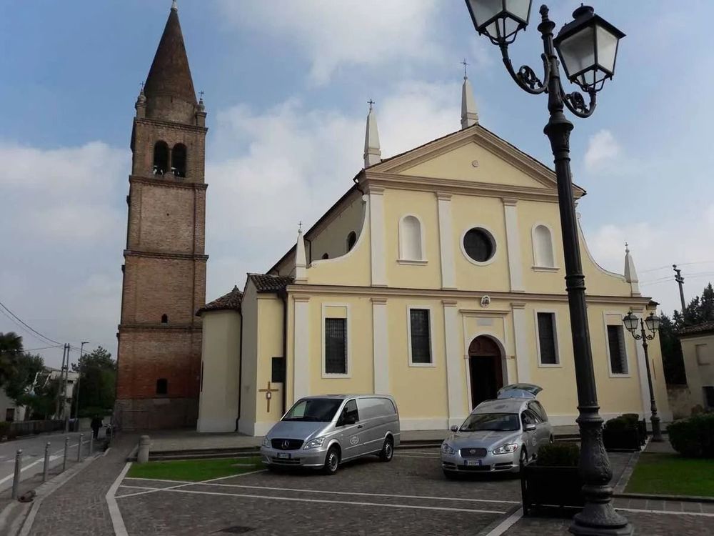 Historic church with brick bell tower, parked cars, and street lamps in a town square