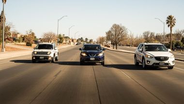 Three cars driving side by side on a wide road in a sunny desert neighborhood