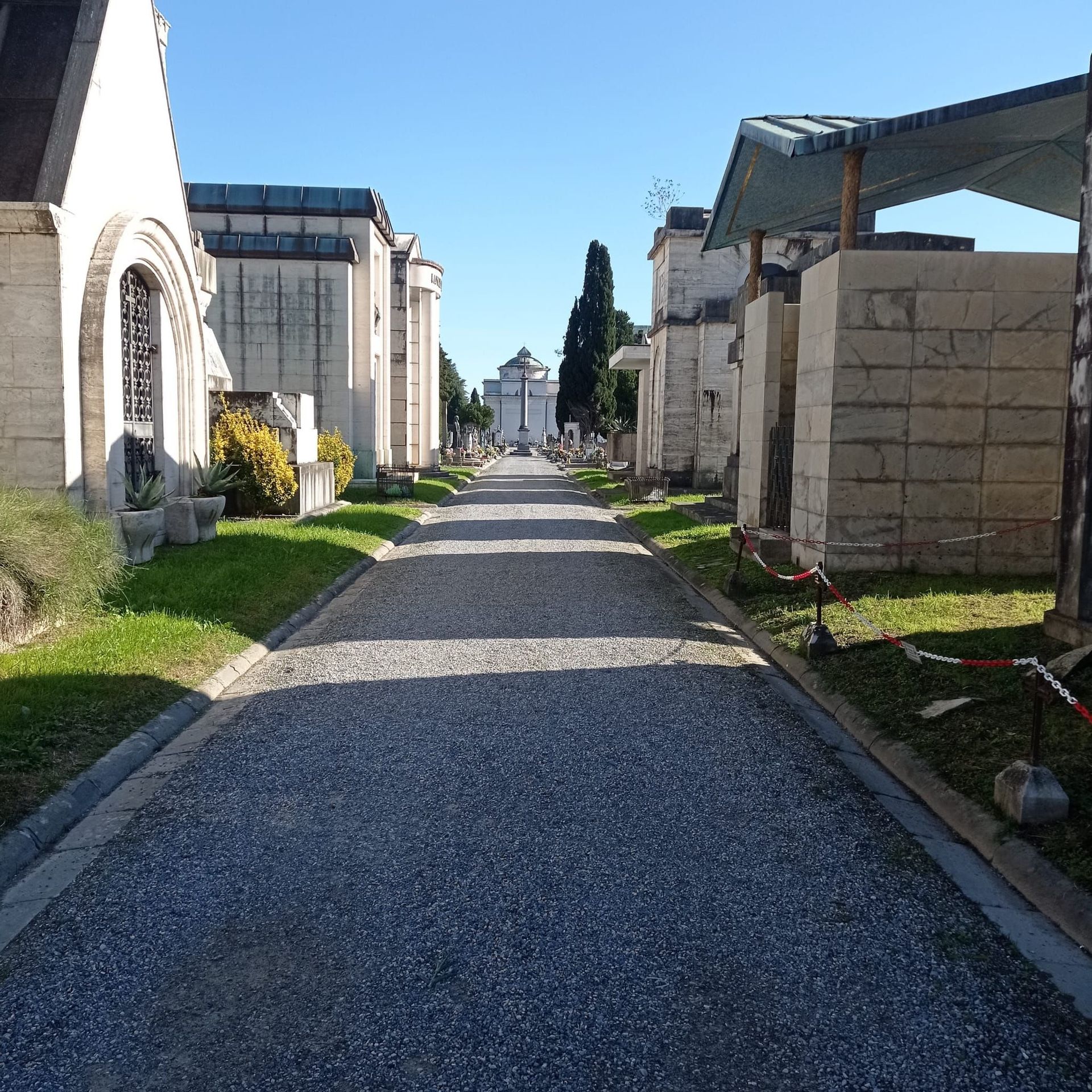 Una strada sterrata che attraversa un cimitero con una croce in lontananza