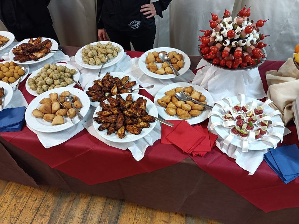 Un tavolo con piatti di cibo sopra e una donna in piedi sullo sfondo