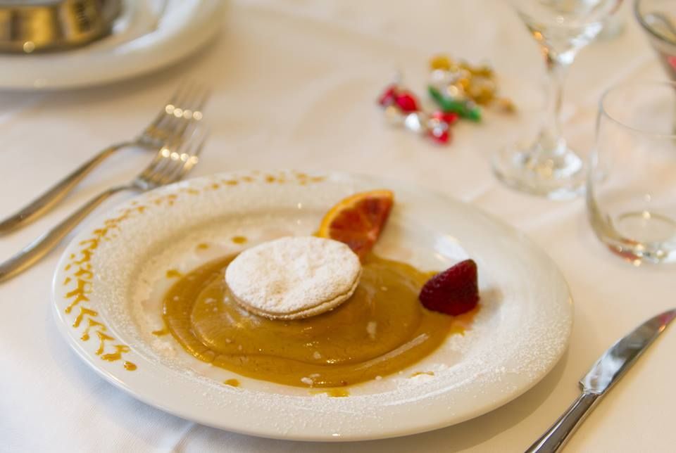 Un piatto bianco con sopra un dolce e una fragola su un tavolo.