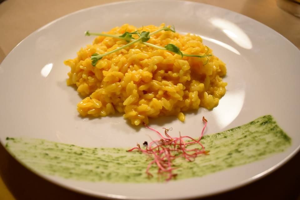 Un piatto bianco condito con riso giallo e salsa verde.