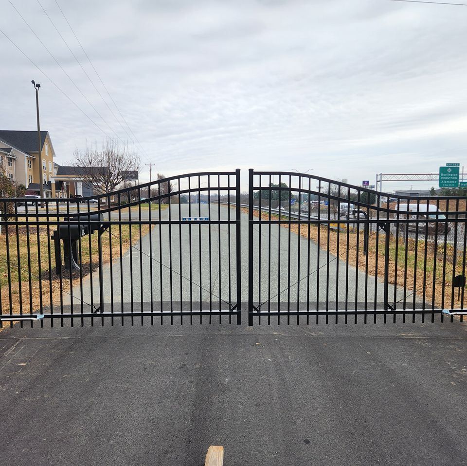 Black metal gate blocking a paved path in a suburban neighborhood under an overcast sky