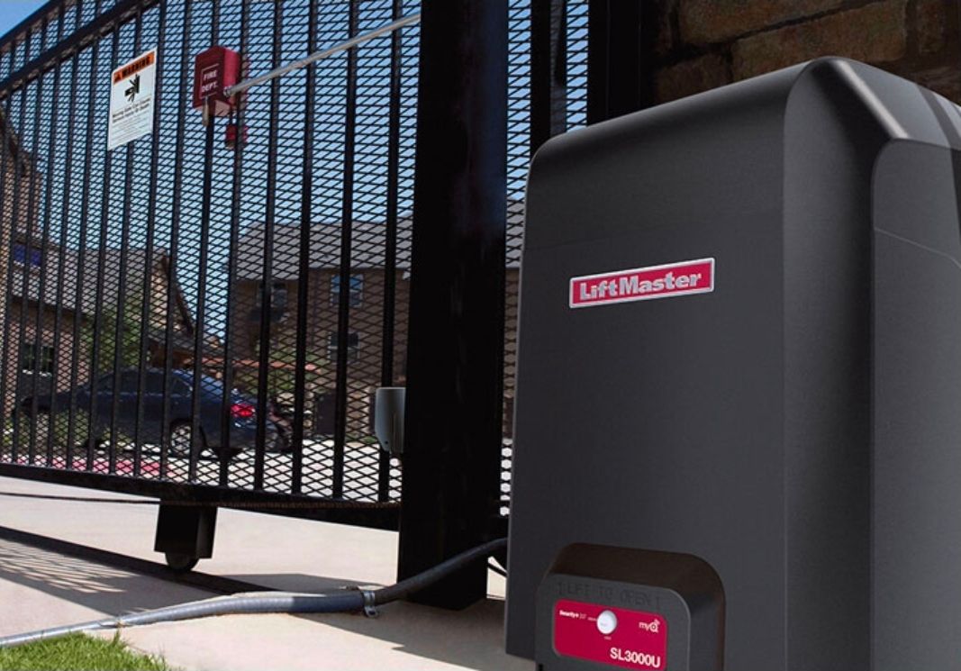 Black sliding gate beside a gray LiftMaster gate opener outdoors