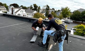 Two men are working on the roof of a building.