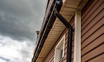 A close up of a gutter on the side of a house.