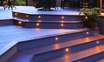 Composite deck steps with inset warm lights leading to a seating area.