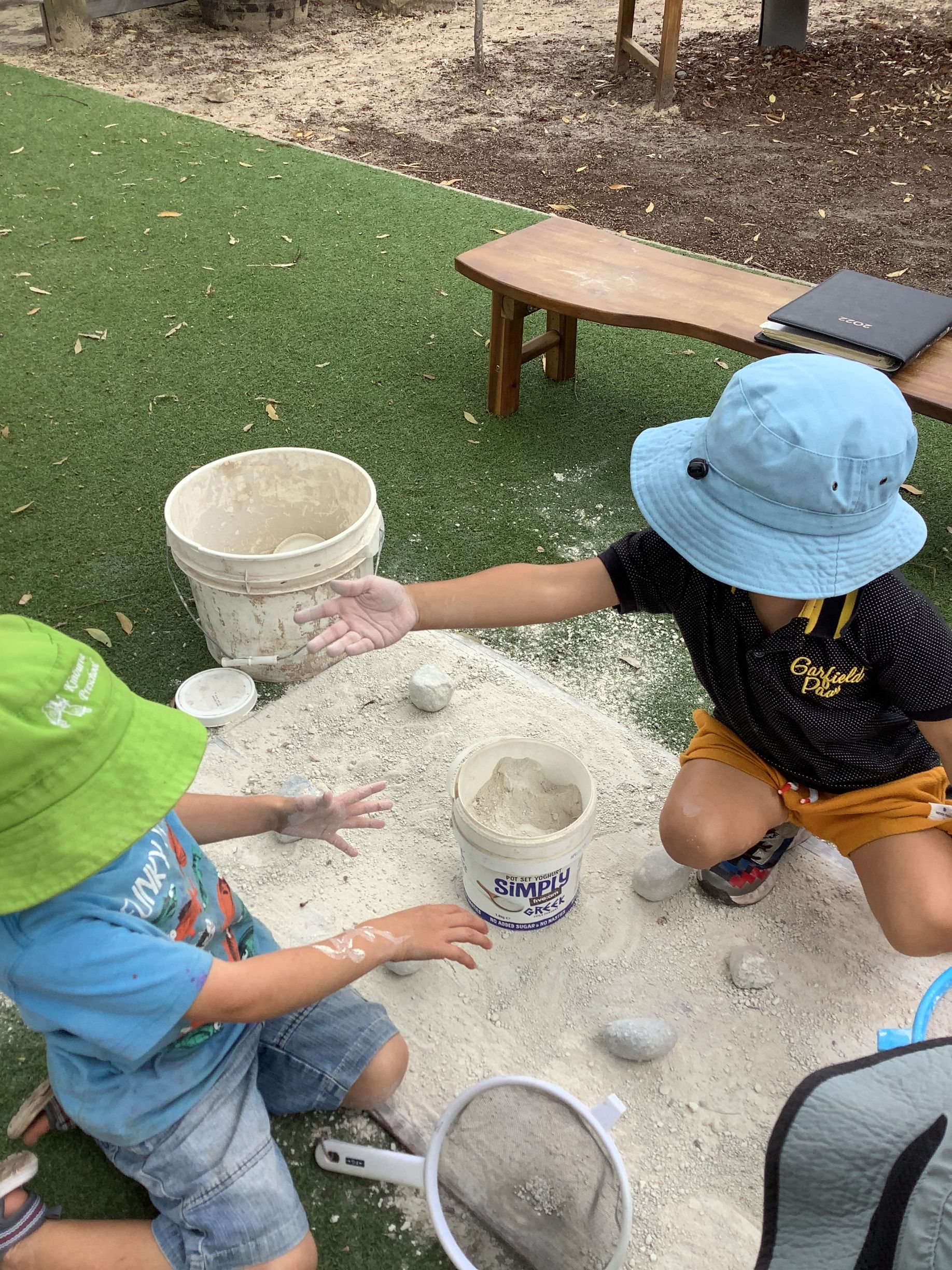 Two children in hats playing with sand in an outdoor setting. — Kinburra Preschool (Kincumber) in Kincumber, NSW