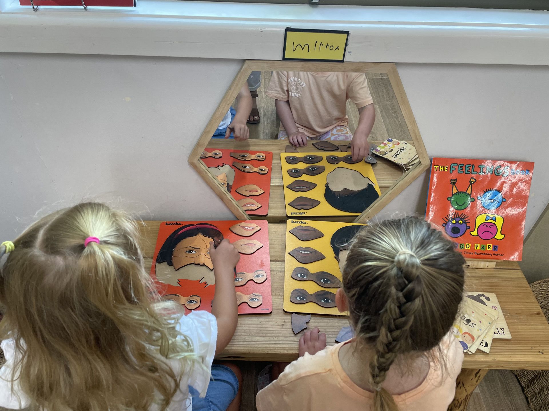 Two girls play a matching game at a table, with a mirror. — Kinburra Preschool (Kincumber) in Kincumber, NSW