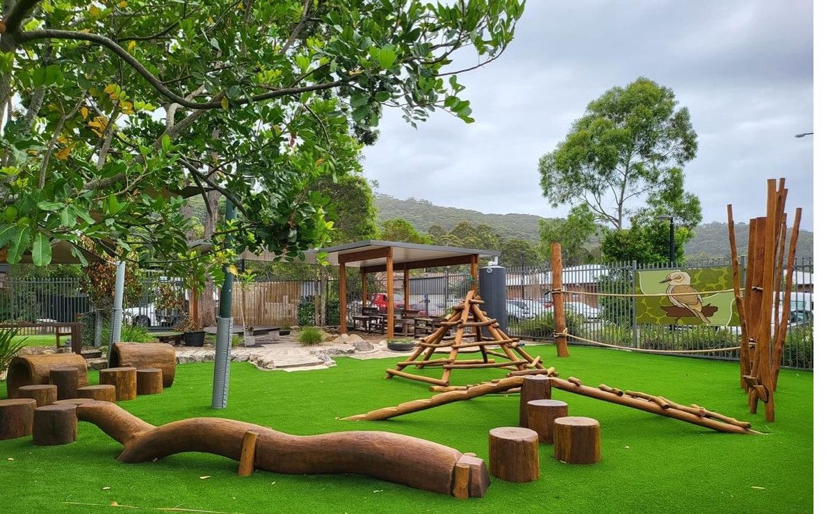 A Group of Logs Sitting on Top of a Lush Green Lawn — Kinburra Preschool (Kincumber) in Kincumber, NSW