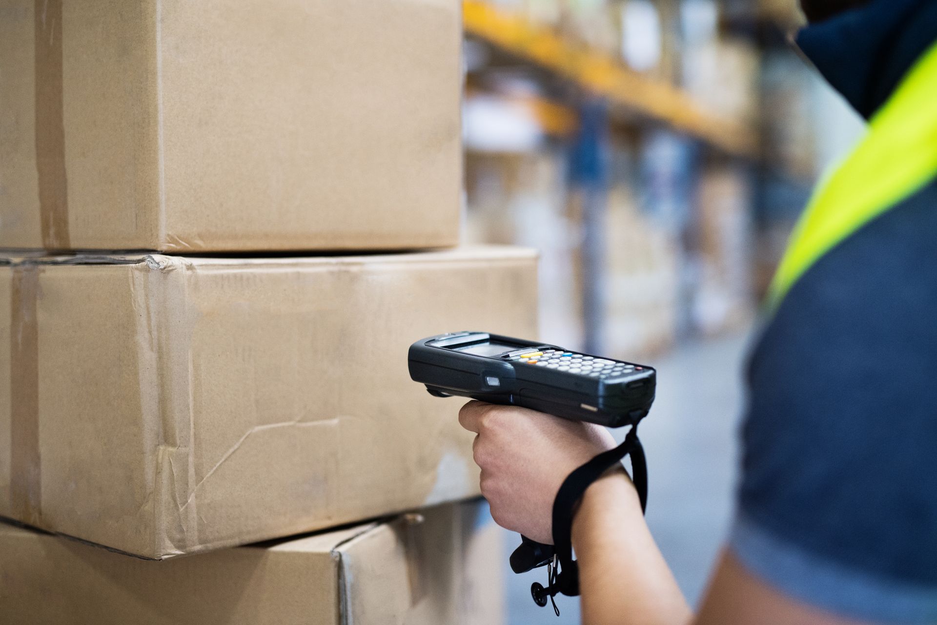 Una persona está utilizando un escáner de código de barras para escanear cajas en un almacén.