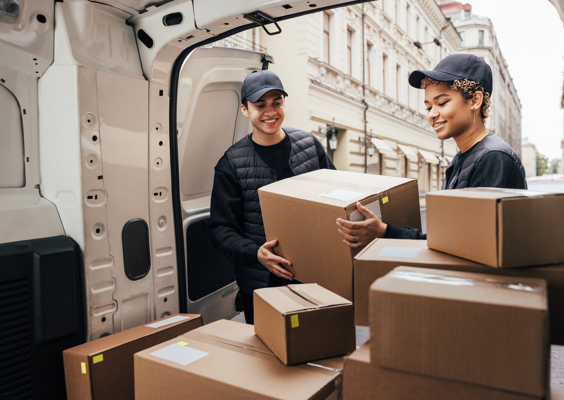 Dos repartidores están cargando cajas en la parte trasera de una camioneta.