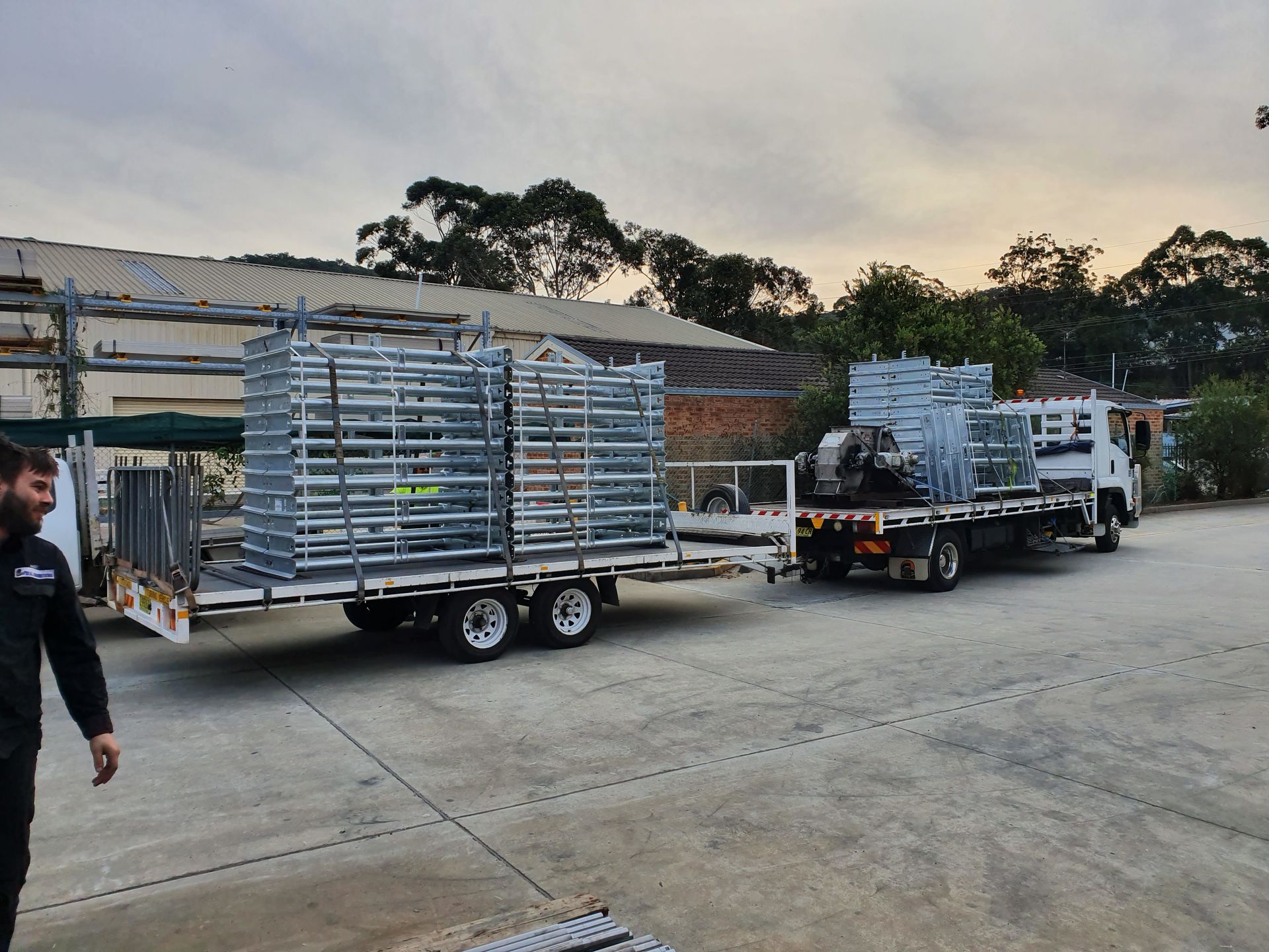 A Man Walks Near a Truck and Trailer Loaded with Stacks of Large — Real Engineering in West Gosford, NSW