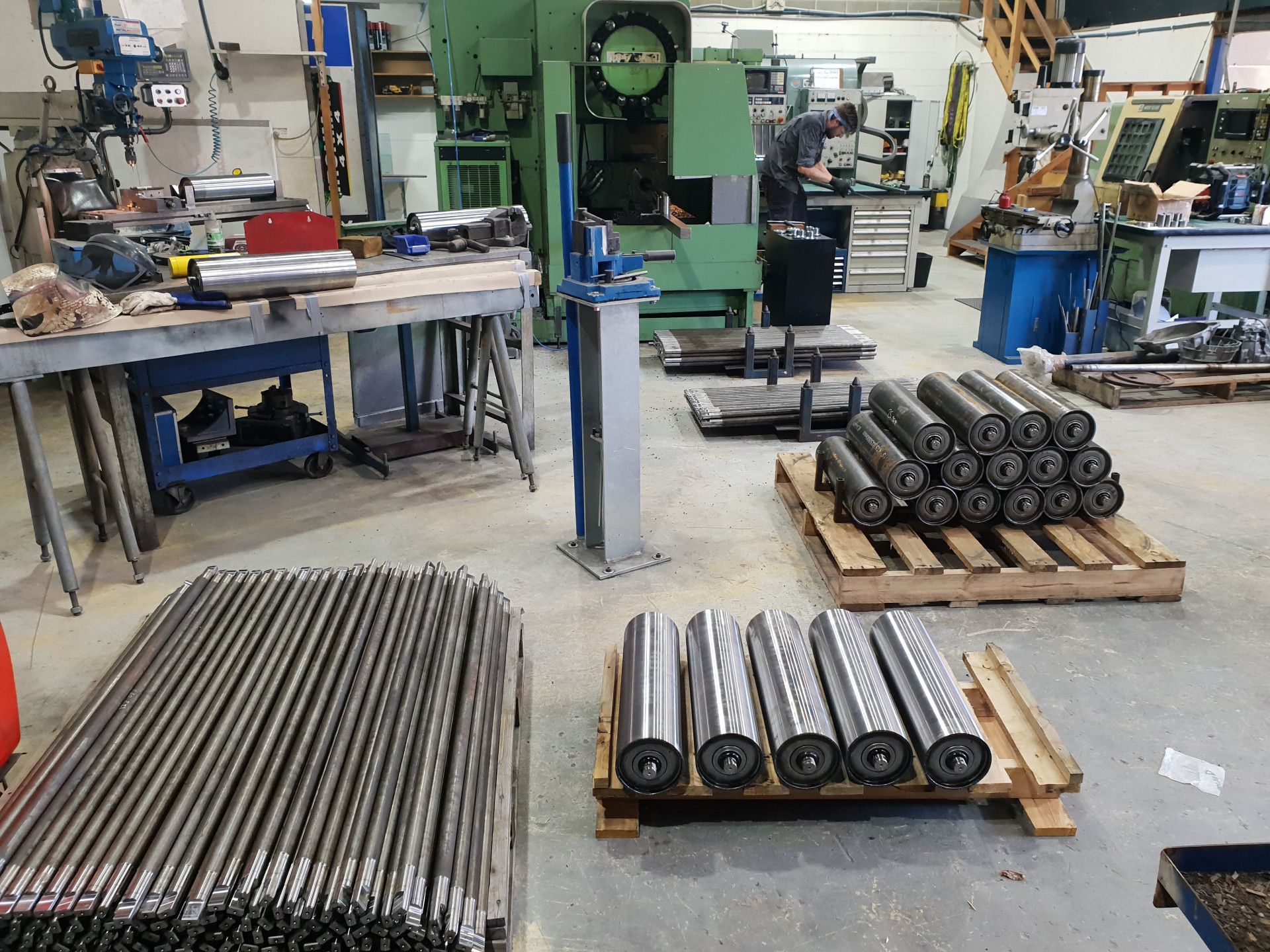A Busy Machine Shop with Industrial Metal Rollers Stacked on Pallets and Workbenches — Real Engineering in West Gosford, NSW