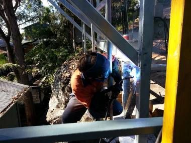 A Worker in A Welding Helmet Uses an Arc Welder on A Metal Structure Outdoors — Real Engineering in West Gosford, NSW