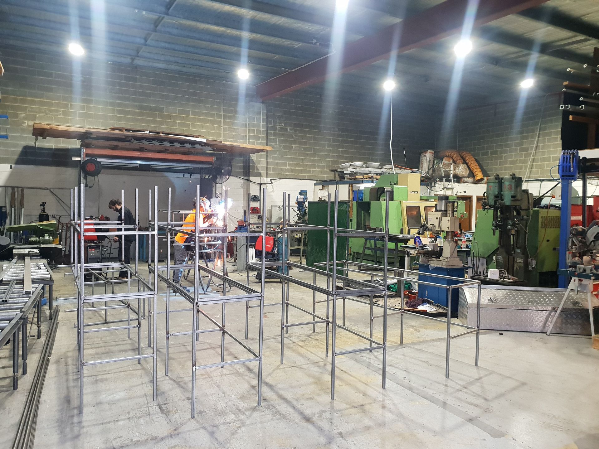 A Worker in An Orange Vest Welds a Metal Frame — Real Engineering in West Gosford, NSW