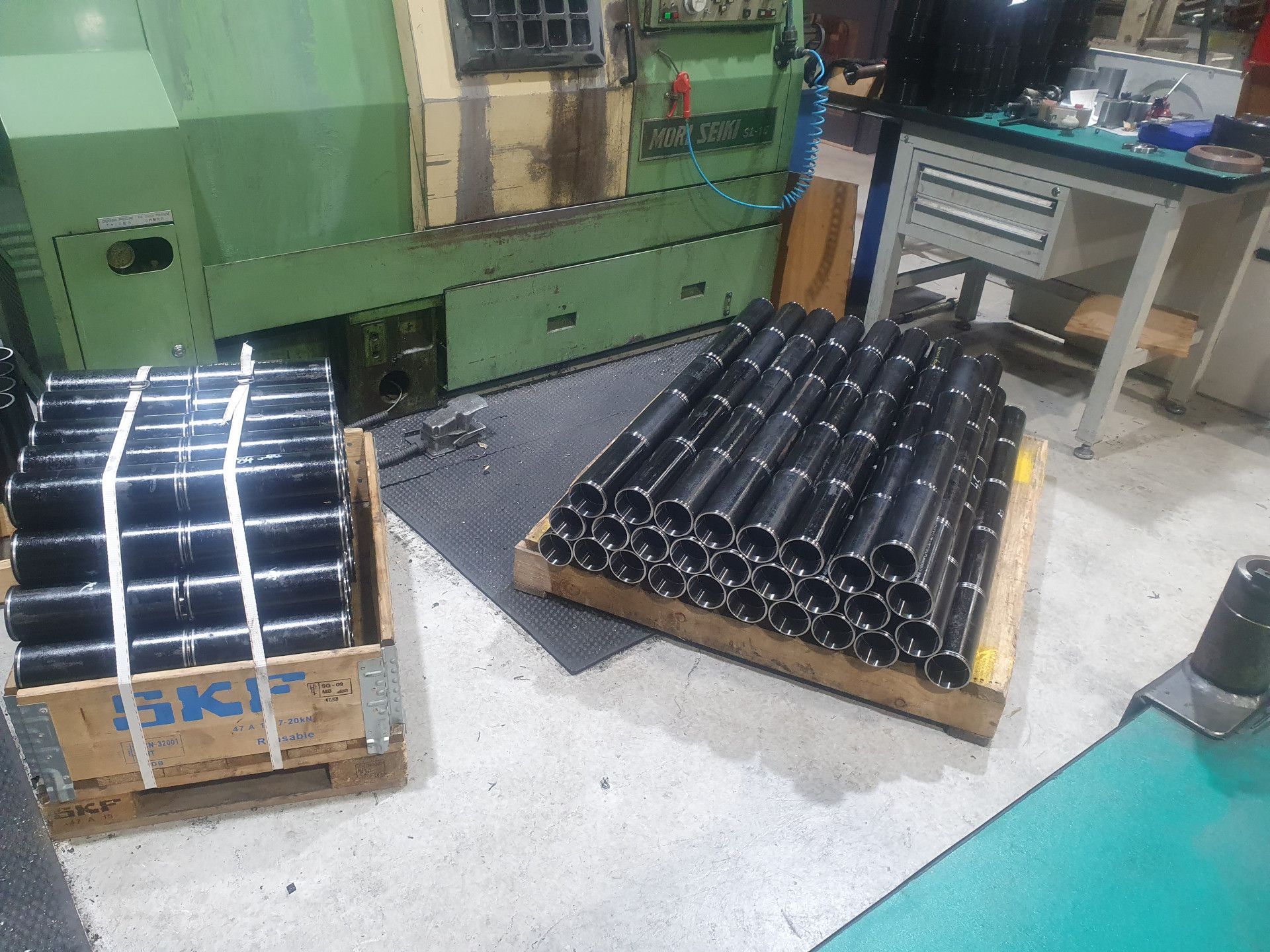 Two Piles of Black Metal Pipes Resting on Wooden Pallets — Real Engineering in West Gosford, NSW