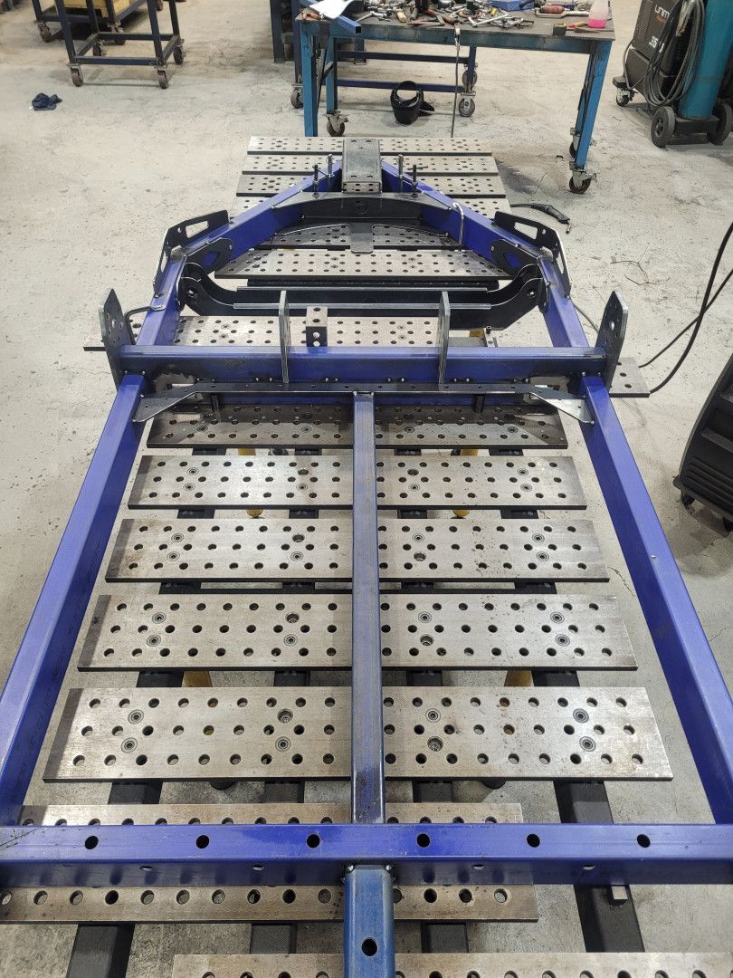 A Blue Metal Frame Assembly Rests on A Flat, Perforated Industrial Welding Table — Real Engineering in West Gosford, NSW