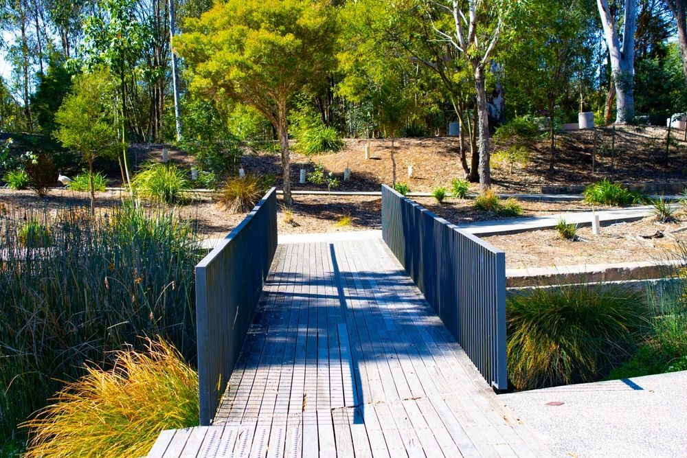 A Wooden Footbridge with Gray Railings Crosses Over a Wetland Area — Real Engineering In Ingleburn, NSW