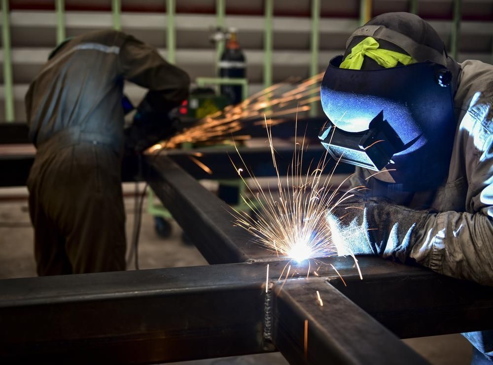 A Man Is Welding A Piece Of Metal In A Factory — Real Engineering In West Gosford, NSW