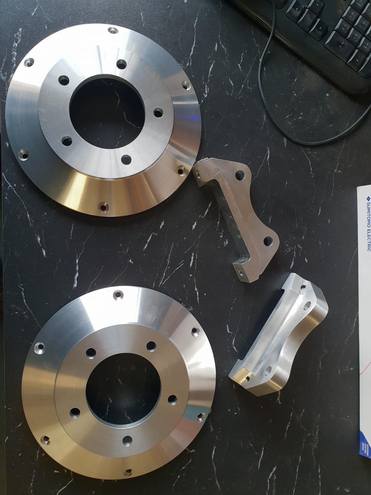 A Pair of Brake Rotors Are Sitting on A Table Next to A Keyboard — Real Engineering In West Gosford, NSW