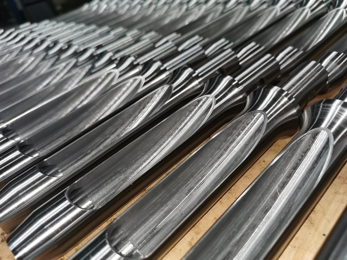 Rows of polished metal pipes or tubes stacked diagonally on a wooden surface — Real Engineering in West Gosford, NSW