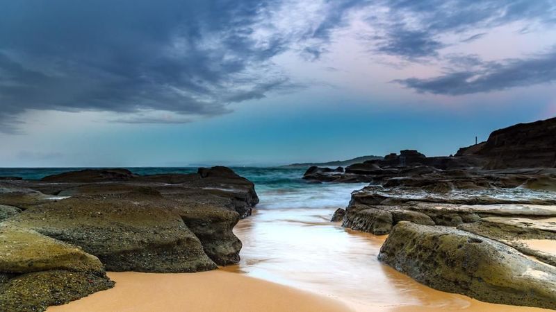A Beach With Rocks And Waves Coming In On A Cloudy Day — Real Engineering In Wyong, NSW