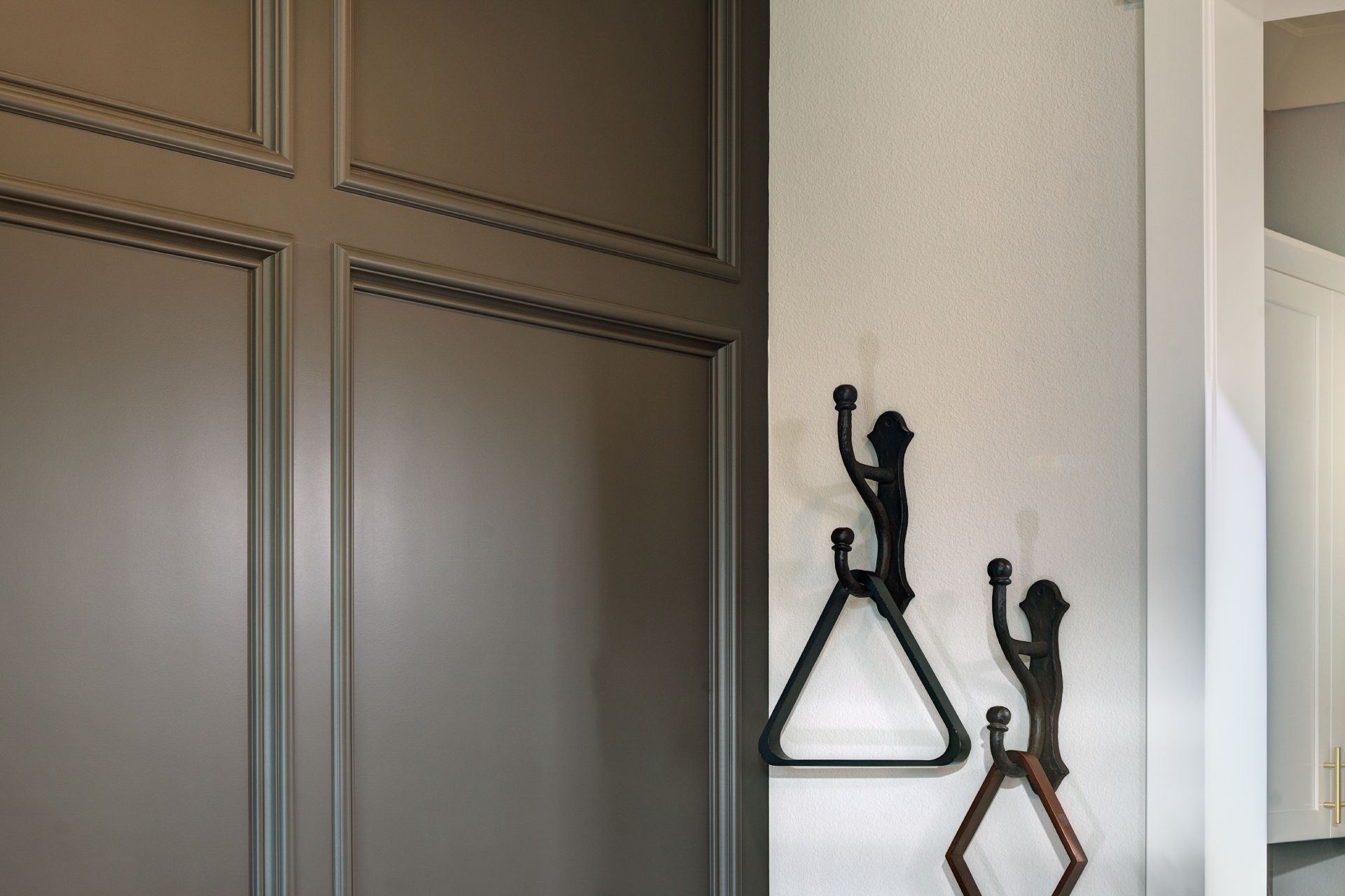Dark gray paneled door with decorative wall hooks on a textured white wall.