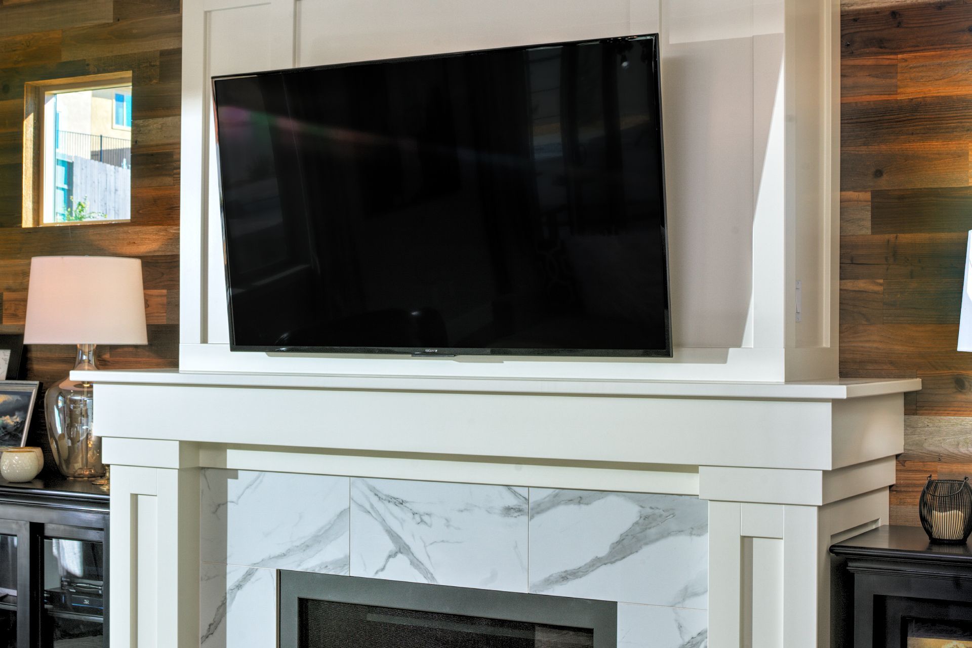TV mounted above a fireplace with white mantel and wood-paneled wall.