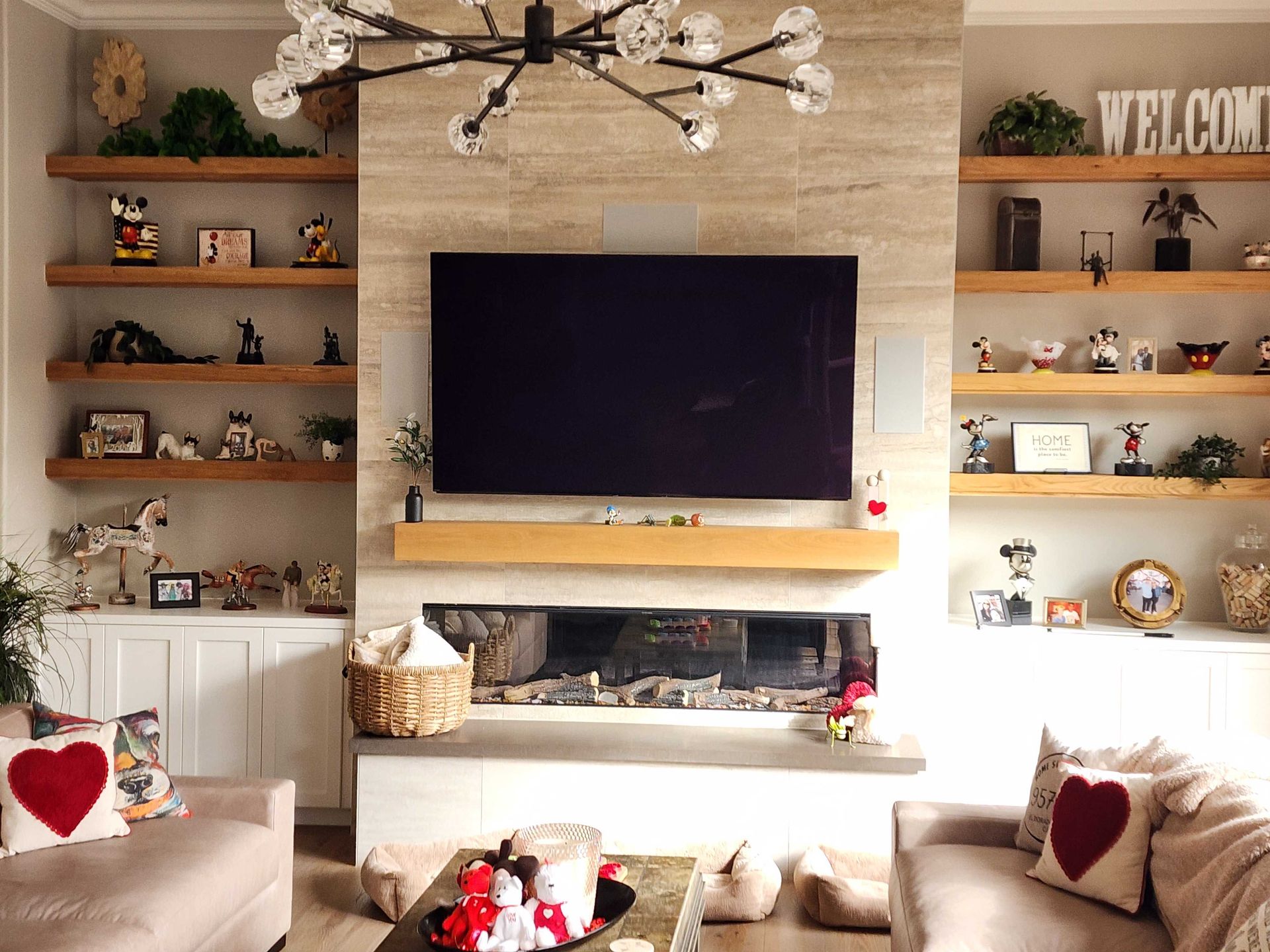 Living room with built-in shelves, a fireplace, and a large TV. Two sofas face the fireplace.