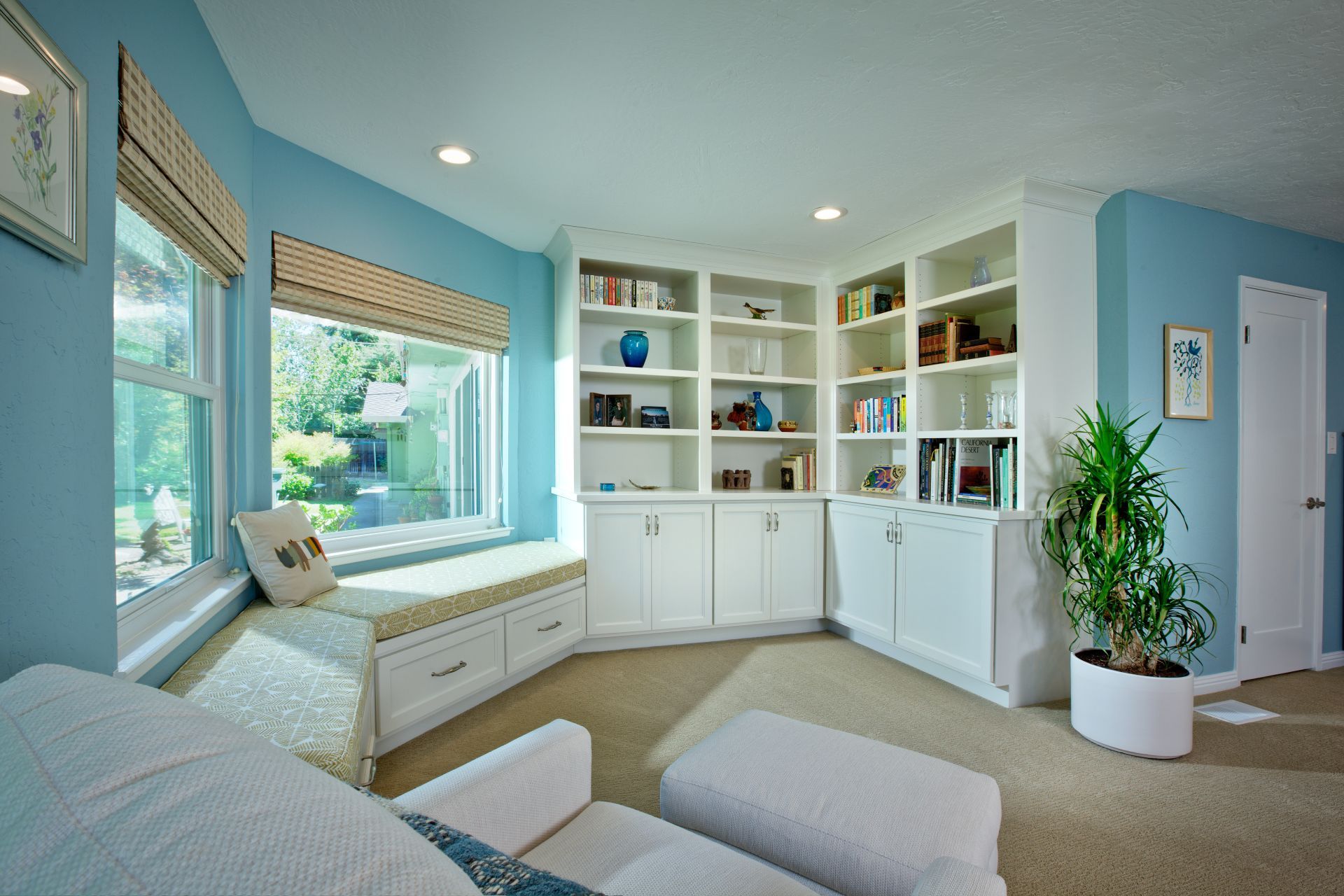 A cozy reading nook with a window seat, built-in bookshelves, and blue walls.