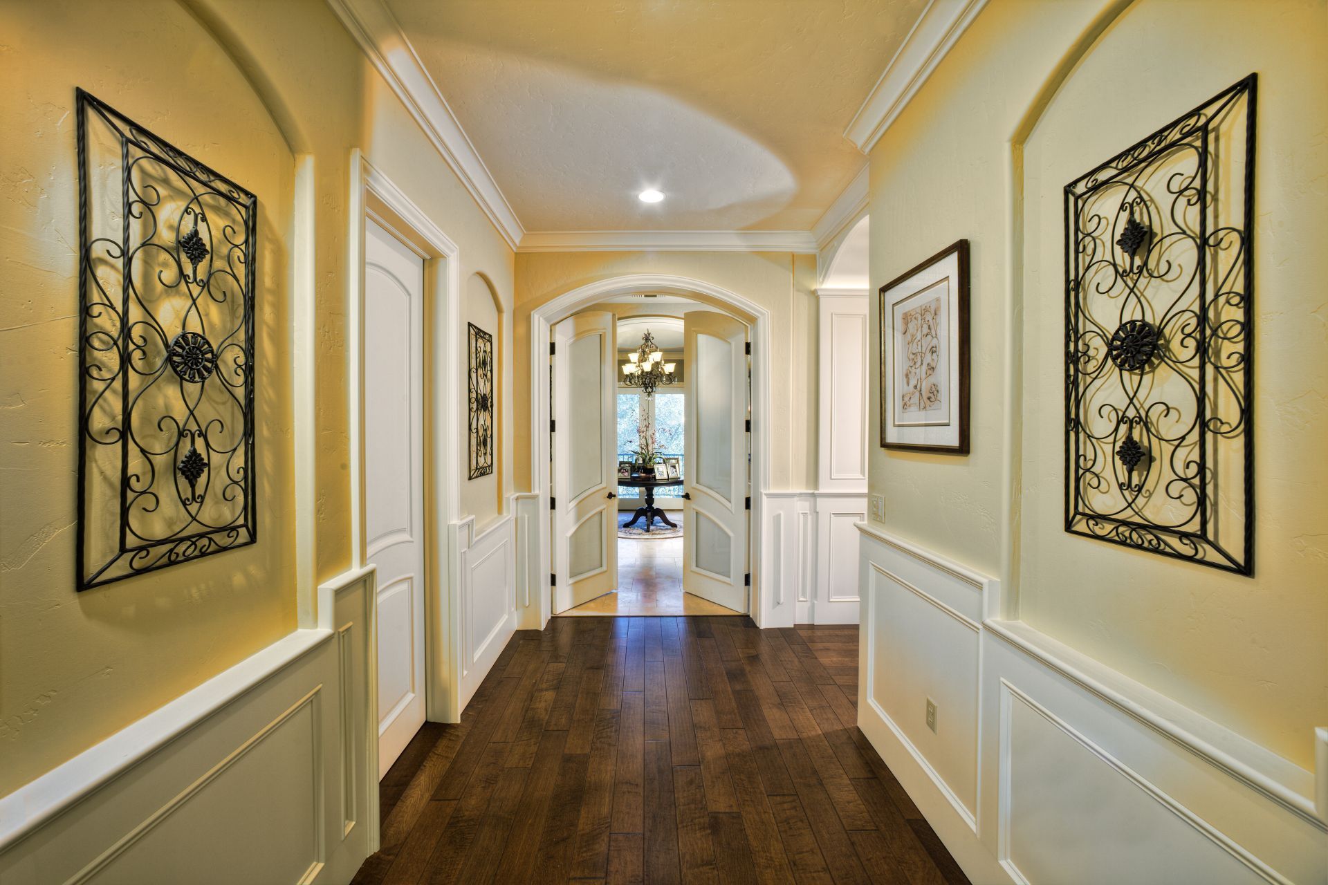 Hallway with dark wood floor, cream walls, and decorative iron wall art.