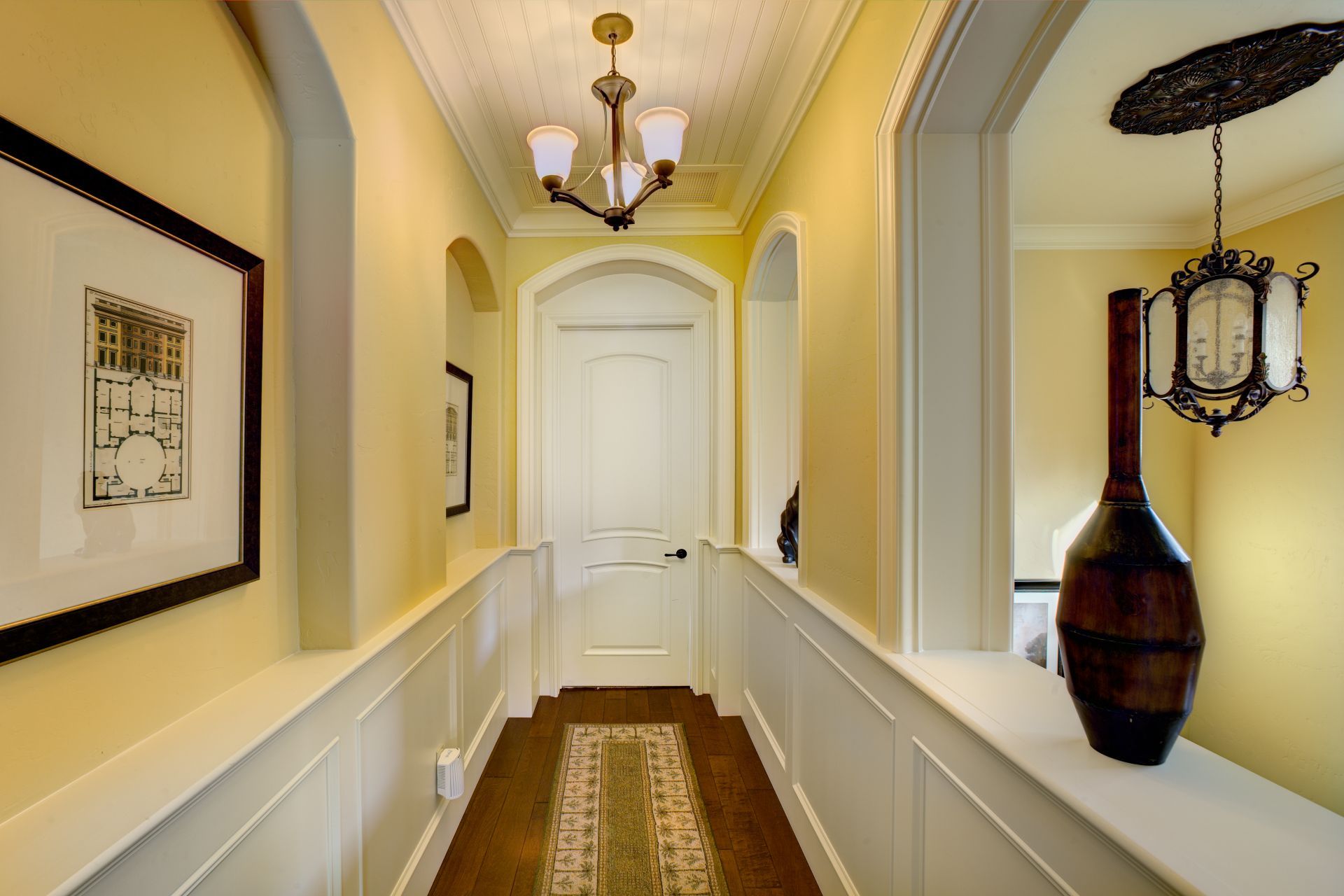 Hallway with yellow walls, white trim, a rug, and a chandelier.