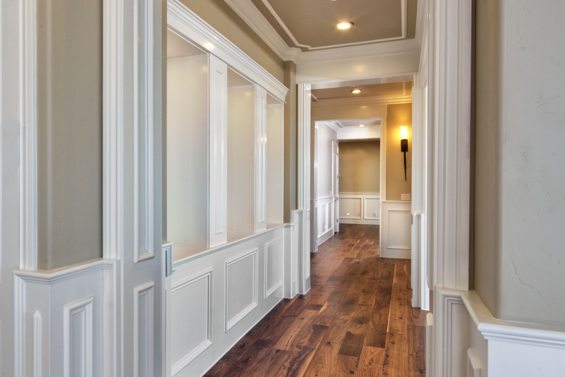 Hallway with white paneling, built-in shelves, and hardwood flooring.