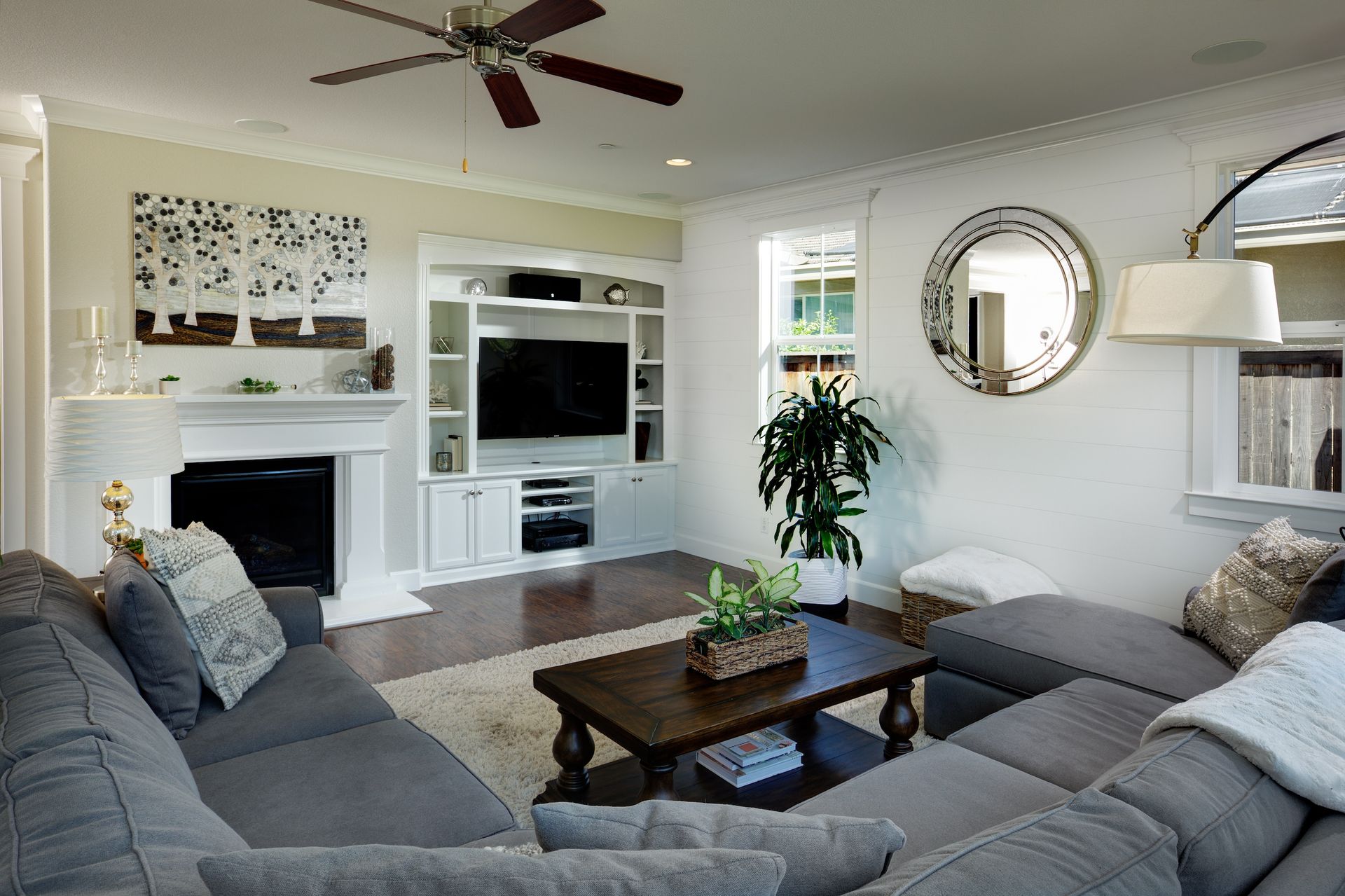 Cozy living room with gray sectional, fireplace, built-in TV, and dark wood coffee table.