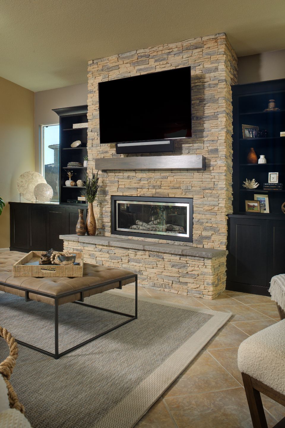 Living room with stone fireplace, built-in bookshelves, TV, and modern furniture.
