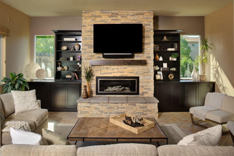 Living room with stone fireplace, black shelving, and light-colored sofas.