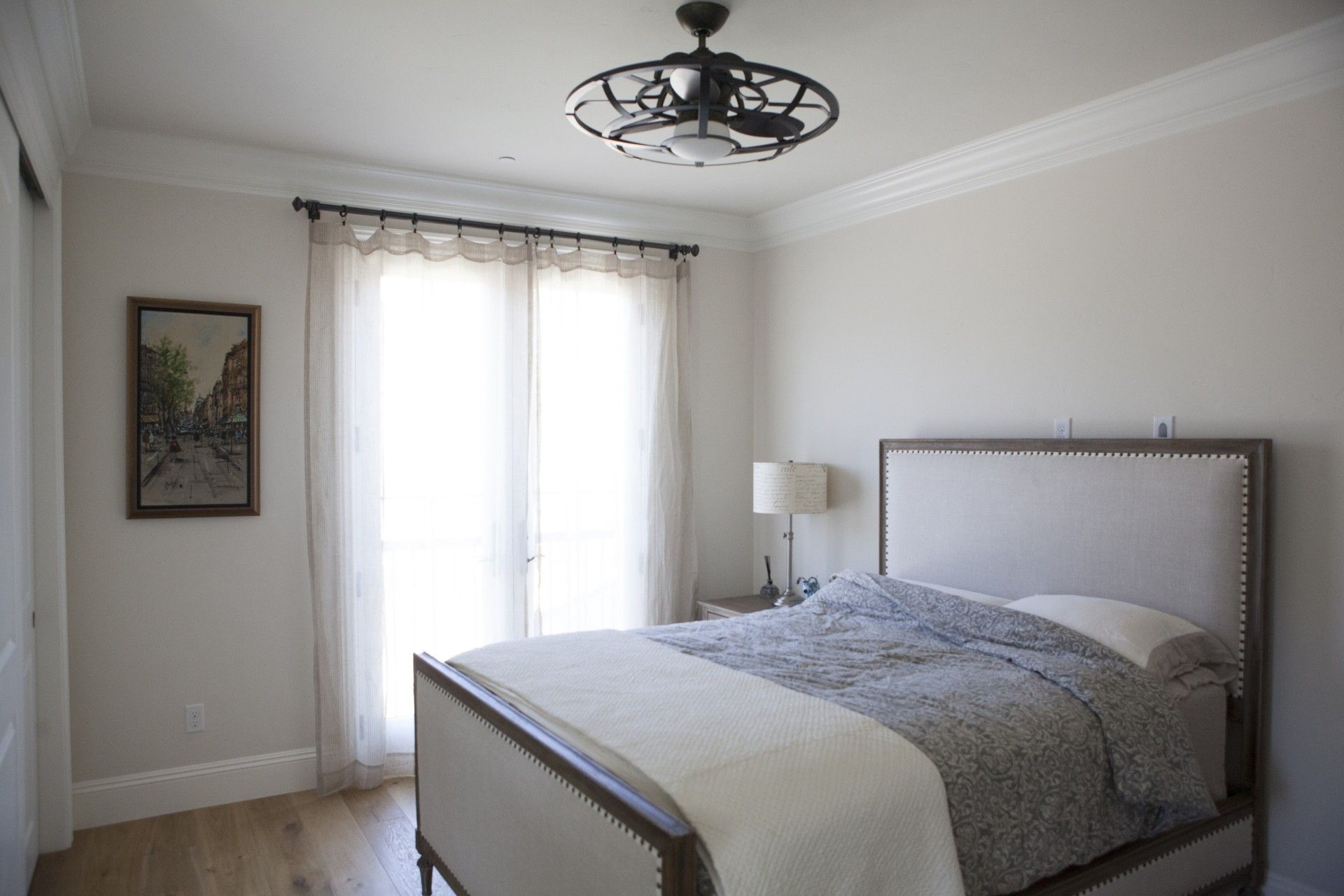 Bedroom with a bed, french doors, a painting, and a ceiling fan.