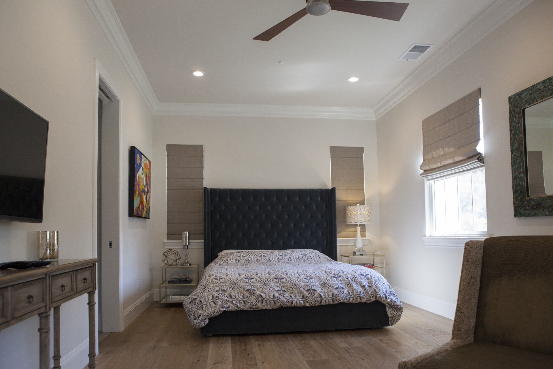 Bedroom with bed, TV, wooden floors, and armchair.