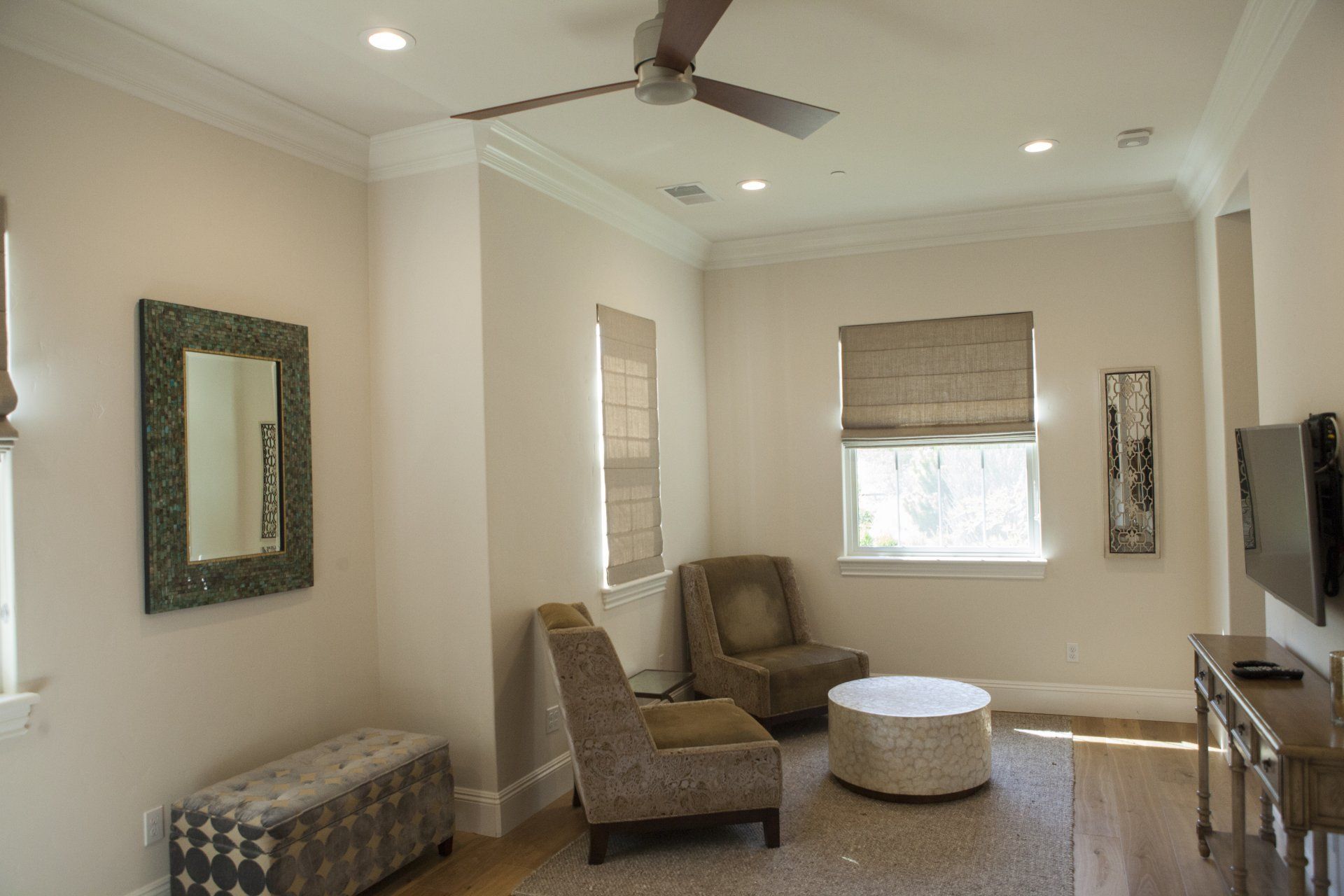 Living room with furniture, mirror, and ceiling fan; beige walls and brown accents.