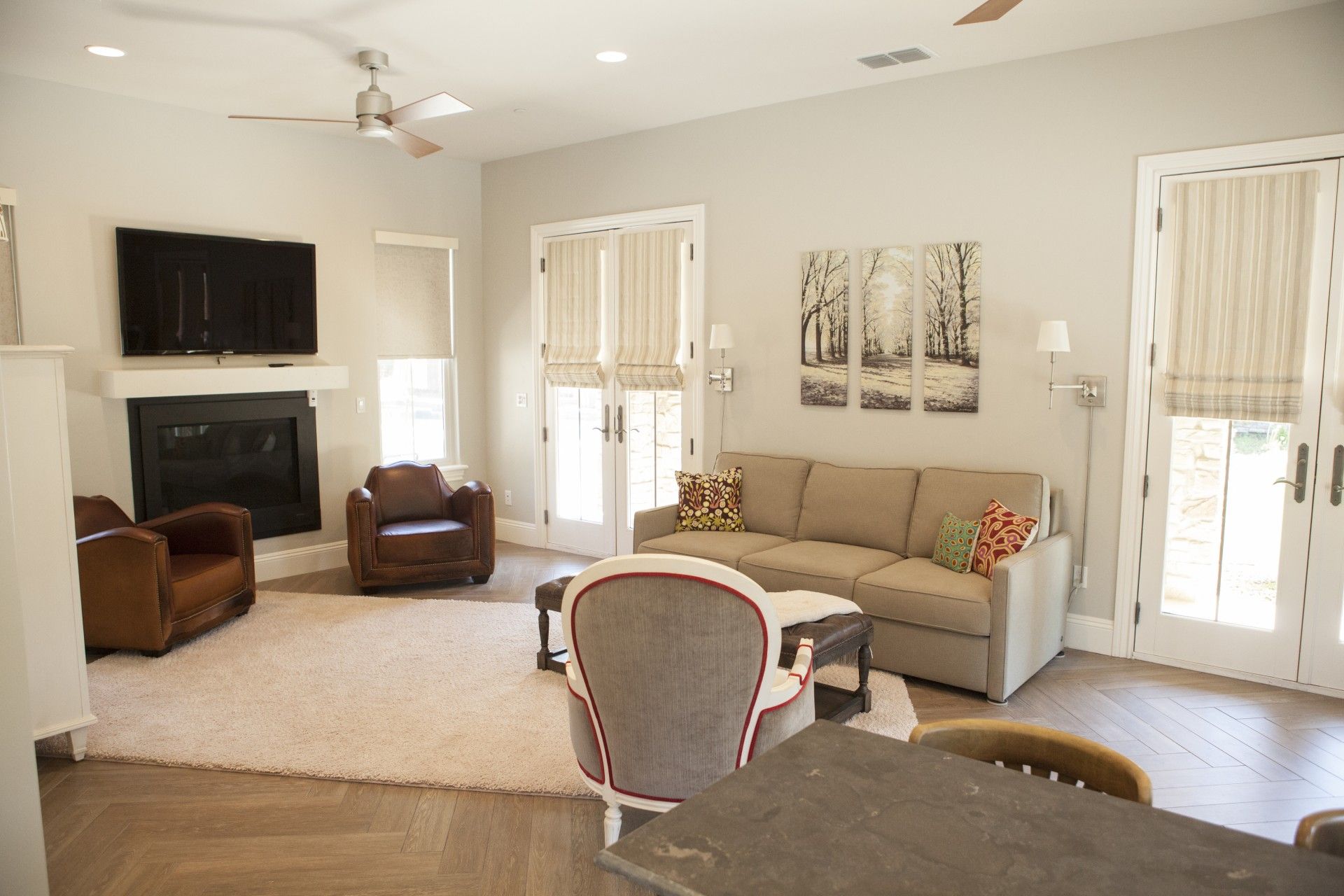Living room with tan sofa, two leather chairs, fireplace, and artwork.