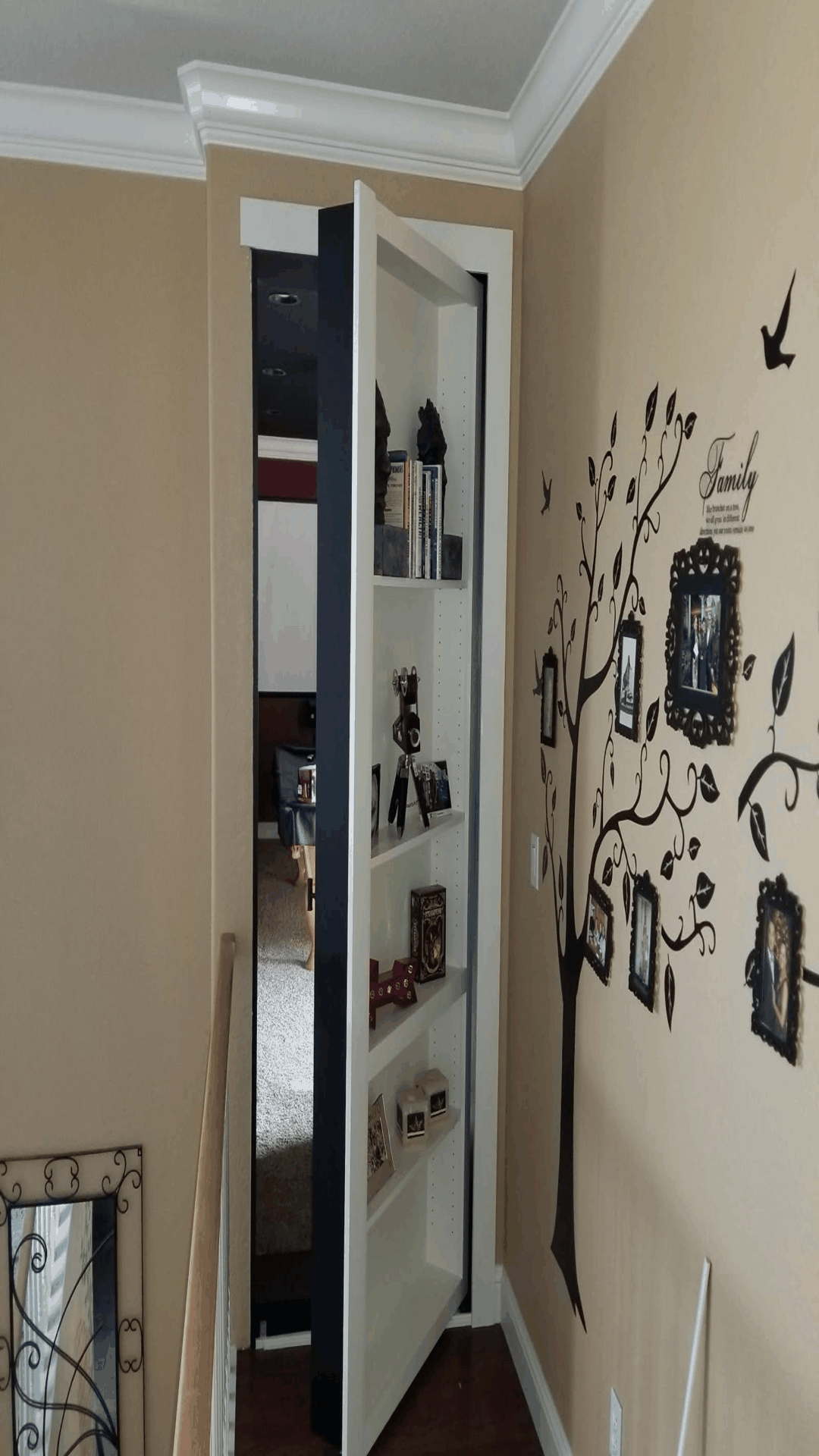 A hidden bookshelf door in a hallway, with items on shelves. The wall has a tree decal.
