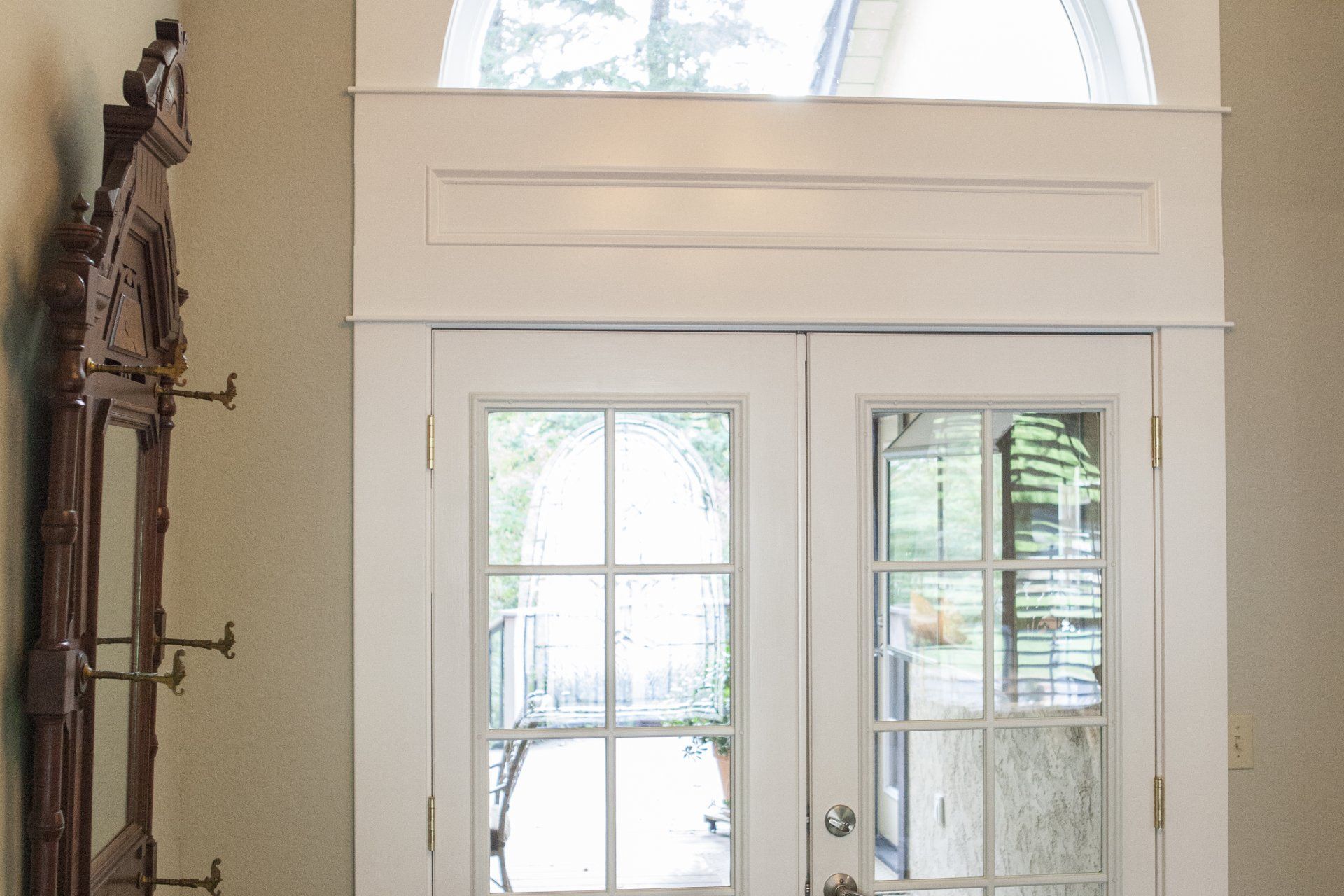 White French doors with arched transom window above; decorative trim.
