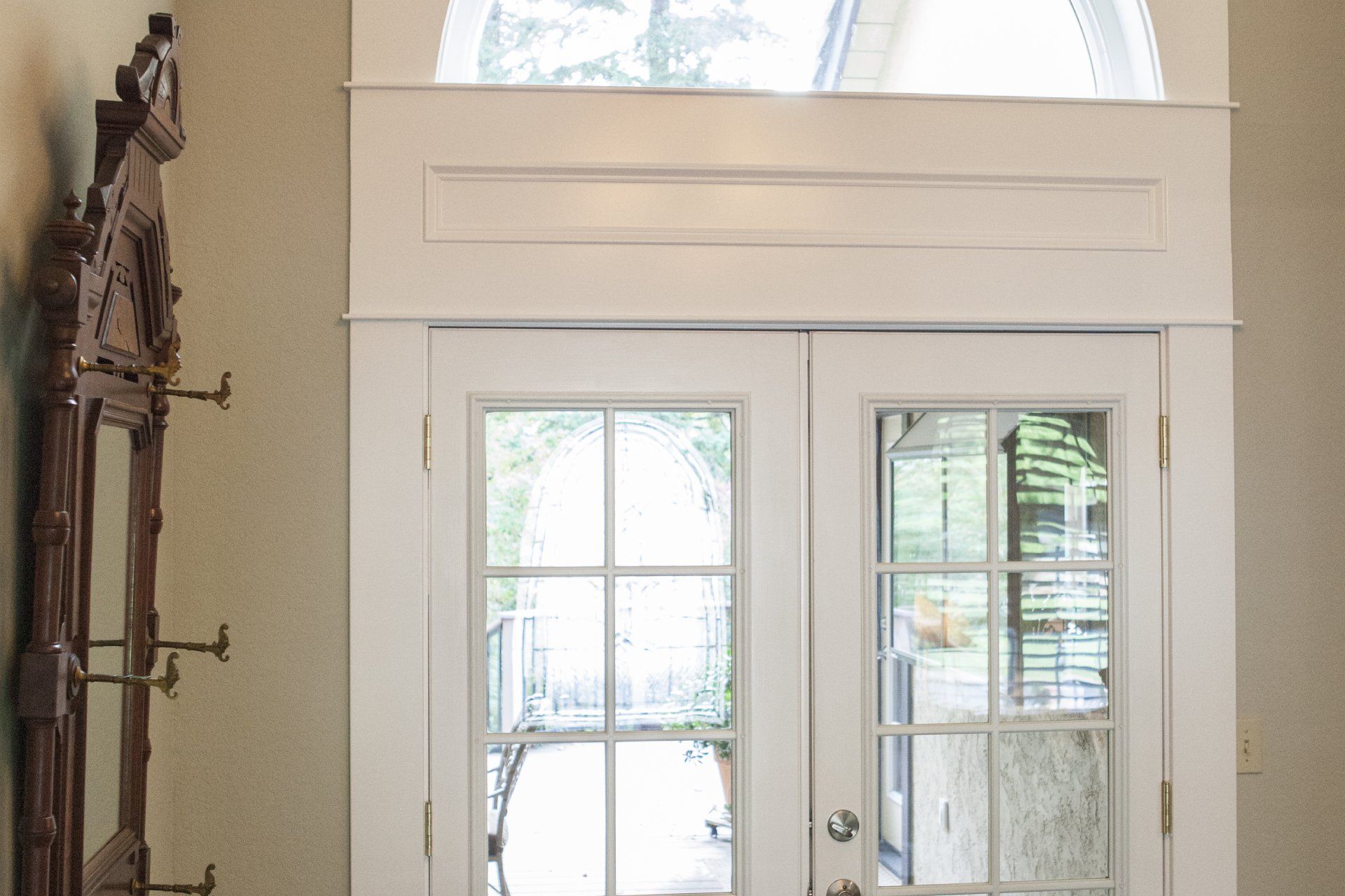 White French doors with glass panes, a decorative wood frame, and a tall ornate mirror.