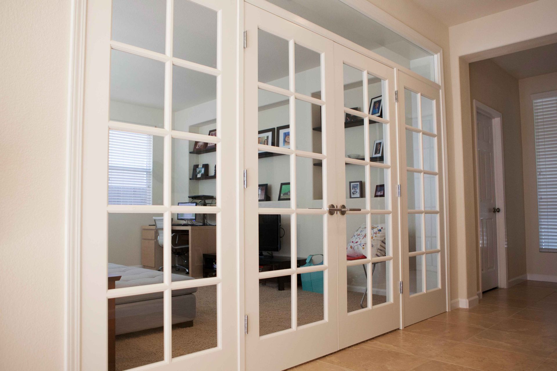 White-framed French doors open to a home office; beige walls and tile floor visible.