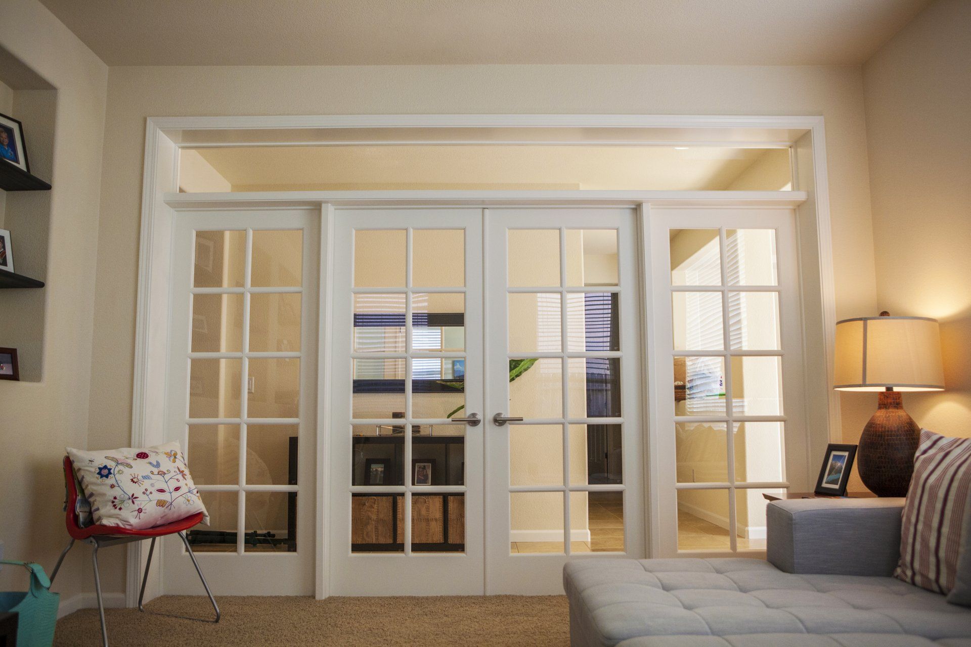 French doors leading to another room; soft lighting, beige walls, couch.